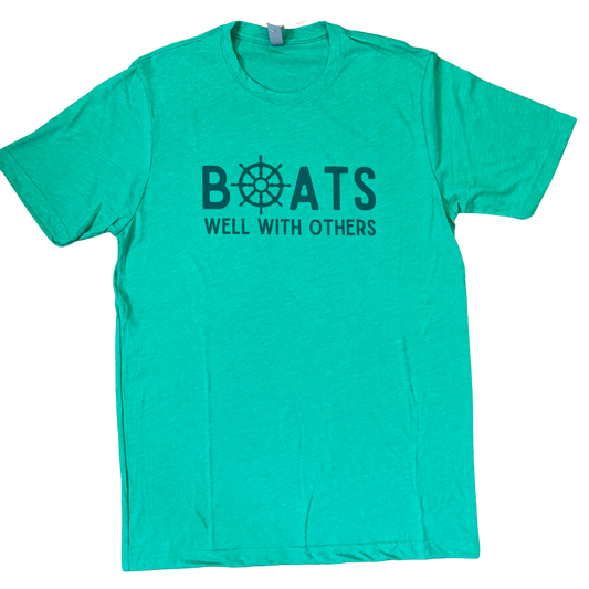 Lay flat of the Boats Well With Others unisex t-shirt in kelly green with blue graphic, showcasing relaxed coastal style