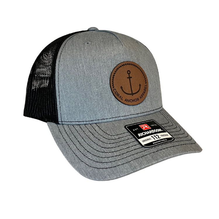 Side angle of Coral Anchor Apparel gray and black Richardson 112 trucker hat with leather anchor patch and mesh back